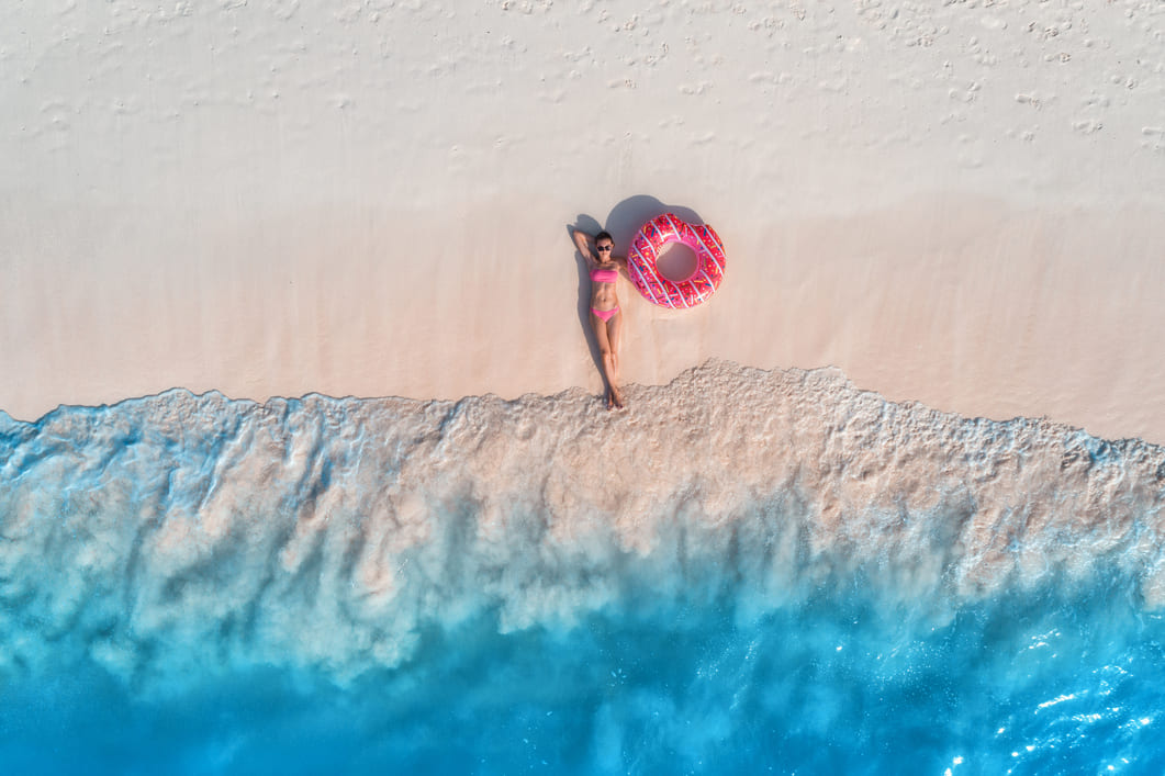 Eine Frau liegt mit Schwimmring am Strand