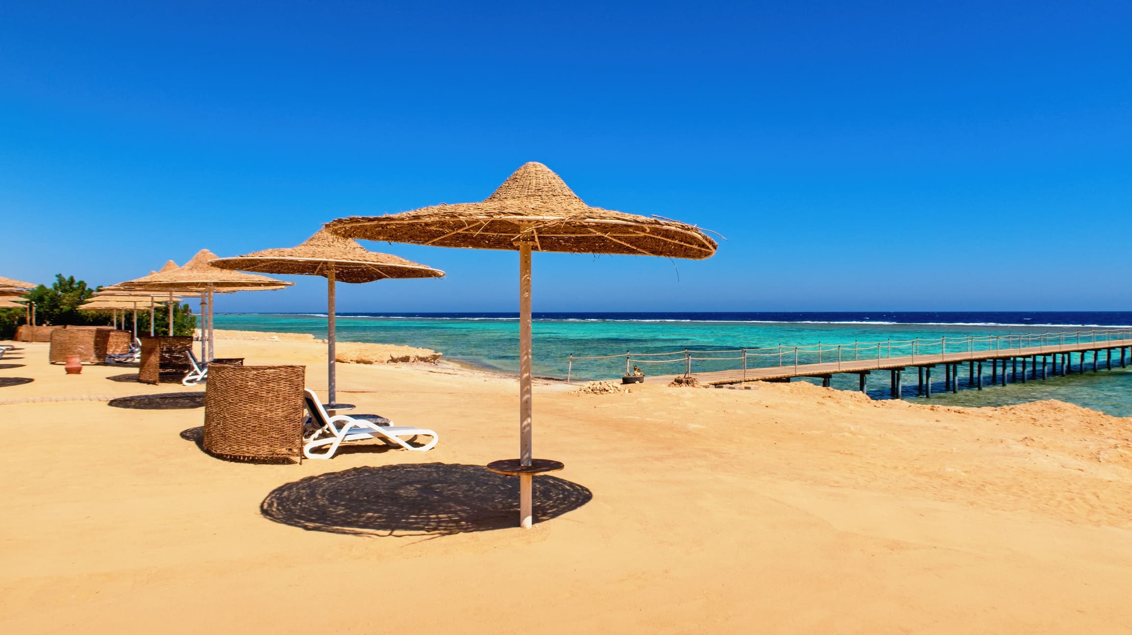 Ägypten Urlaub Goldgelber Strand mit Sonnenschirmen und Sonnenliege