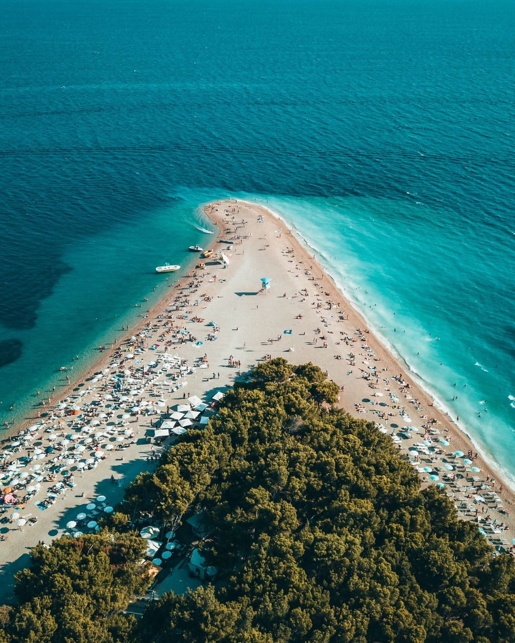 Spitz zulaufende Kiesel-Strand-Bucht mit grünen Büschen