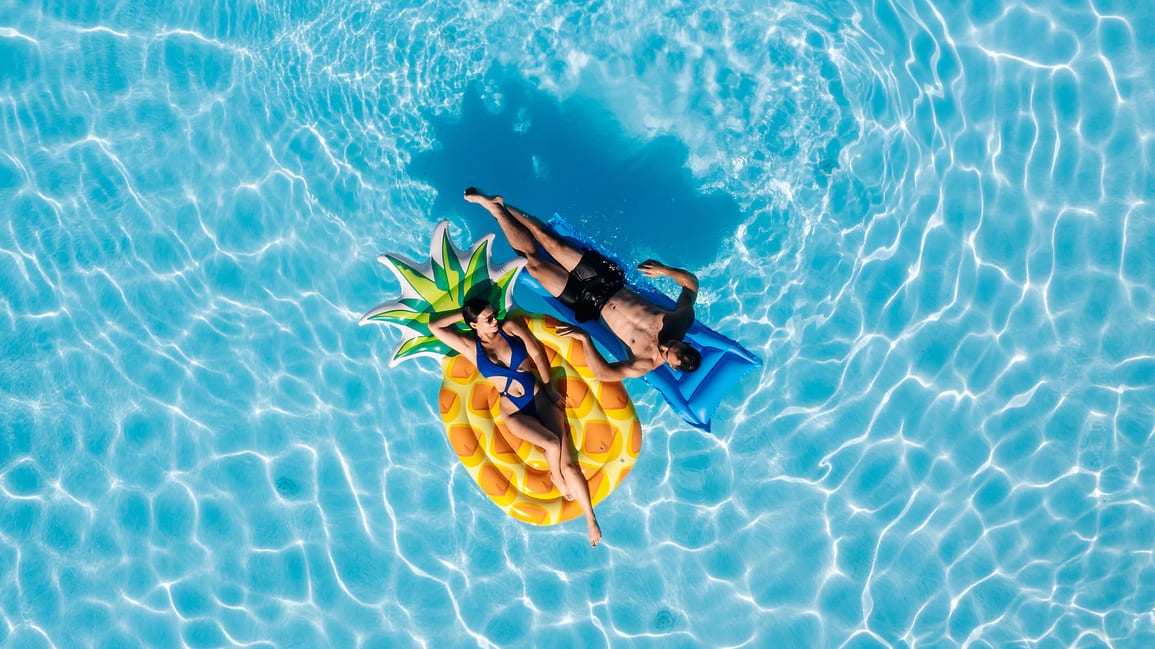 Urlaub im August Ein Pärchen auf Luftmatratzen im Pool