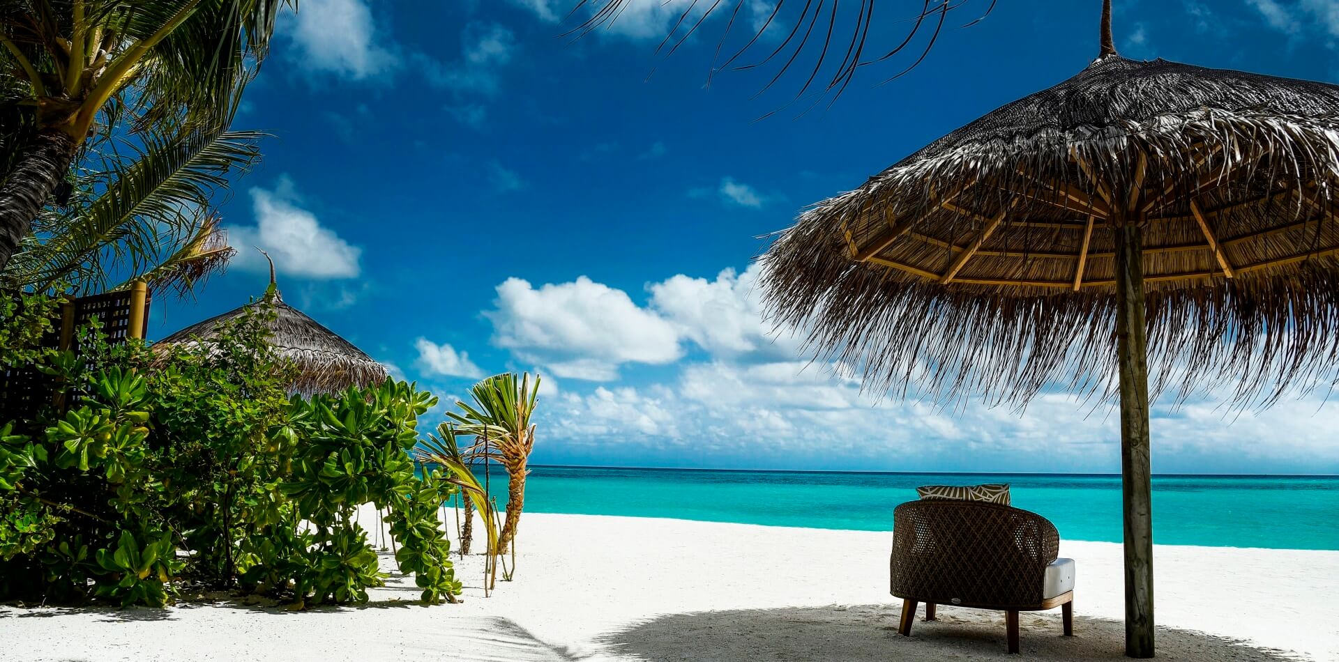 Weißer Strandabschnitte mit Palme und Sonnenschirm